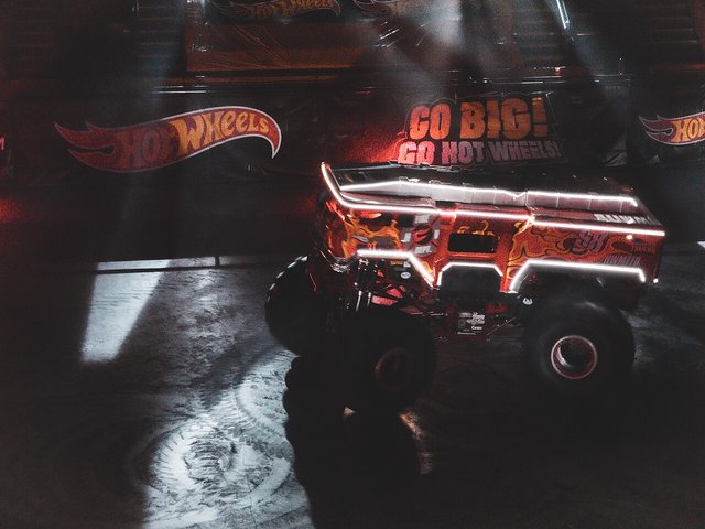 The HW 5-Alarm monster truck outlined in glowing light strips on a dark arena floor under a Go Big Go Hot Wheels sign