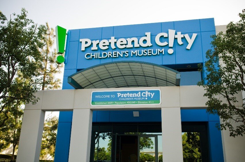 Blue entrance of Pretend City Children's Museum with the museum name in white letters and a green exclamation point