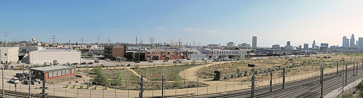 Wide view of the open grounds at Los Angeles State Historic Park with the downtown skyline in the distance