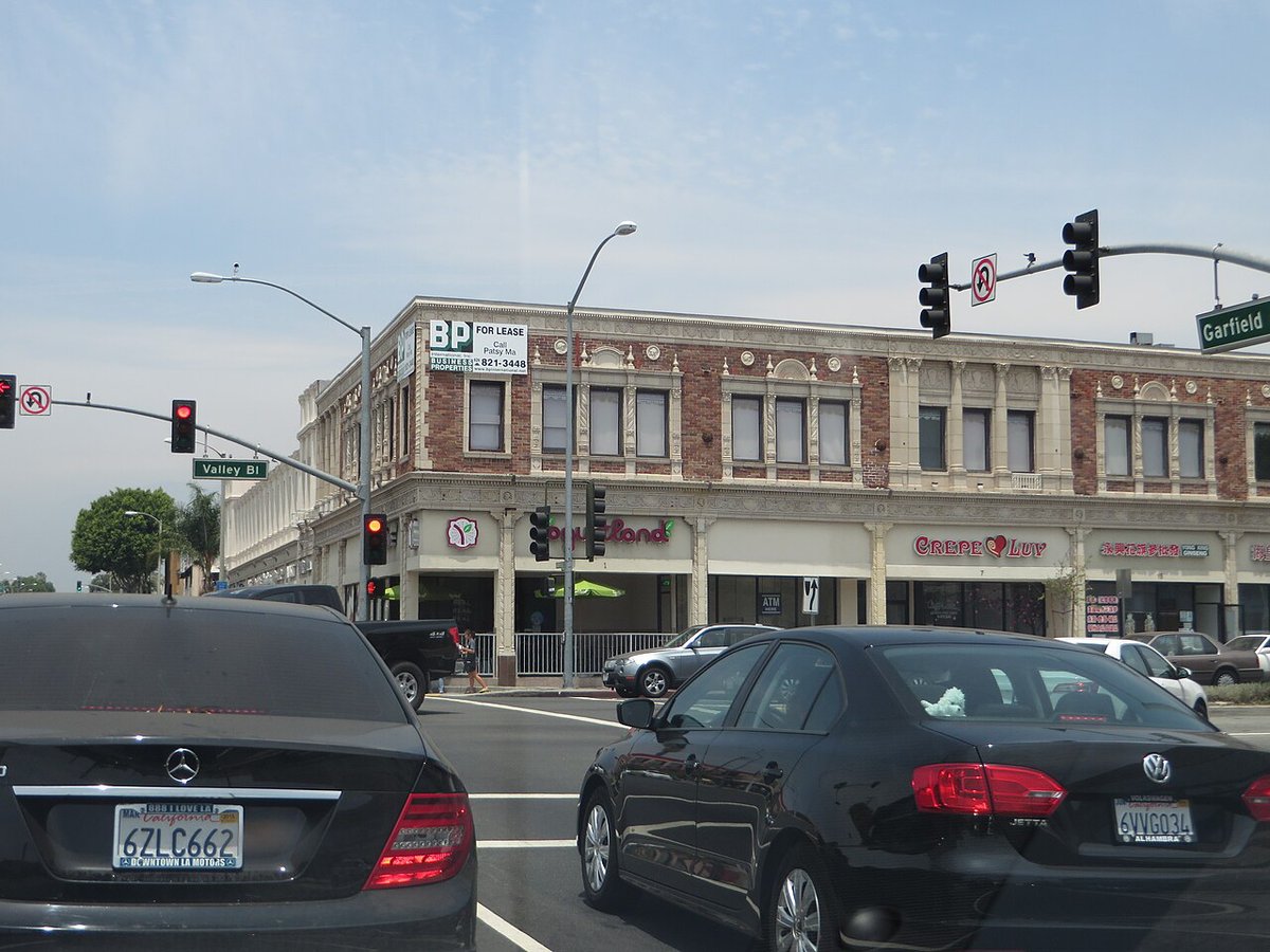 Street view along Garfield Avenue in Alhambra, California, with storefronts and parked cars