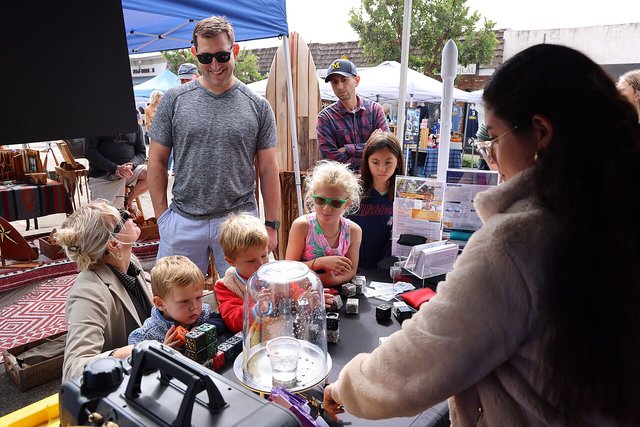 Kids and parents gather at a hands-on science booth under a pop-up tent at the El Segundo Main Street Fair