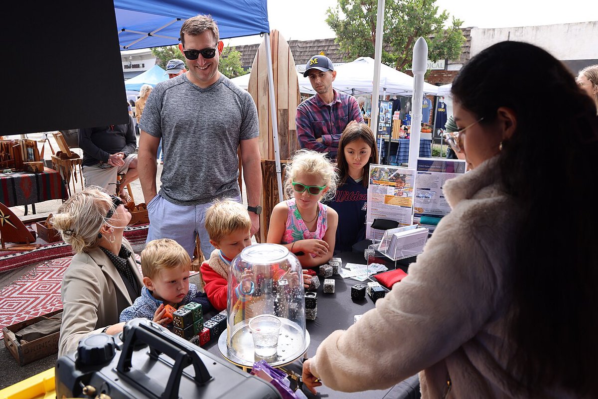 Kids and parents gather at a hands-on science booth under a pop-up tent at the El Segundo Main Street Fair