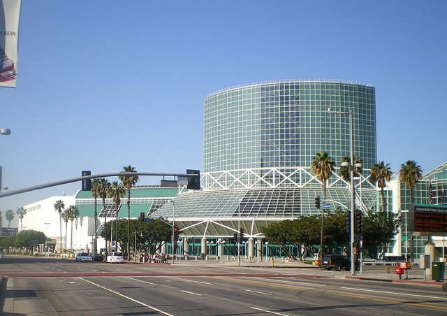 Glass tower and canopy entrance of the Los Angeles Convention Center seen from the street under a clear blue sky