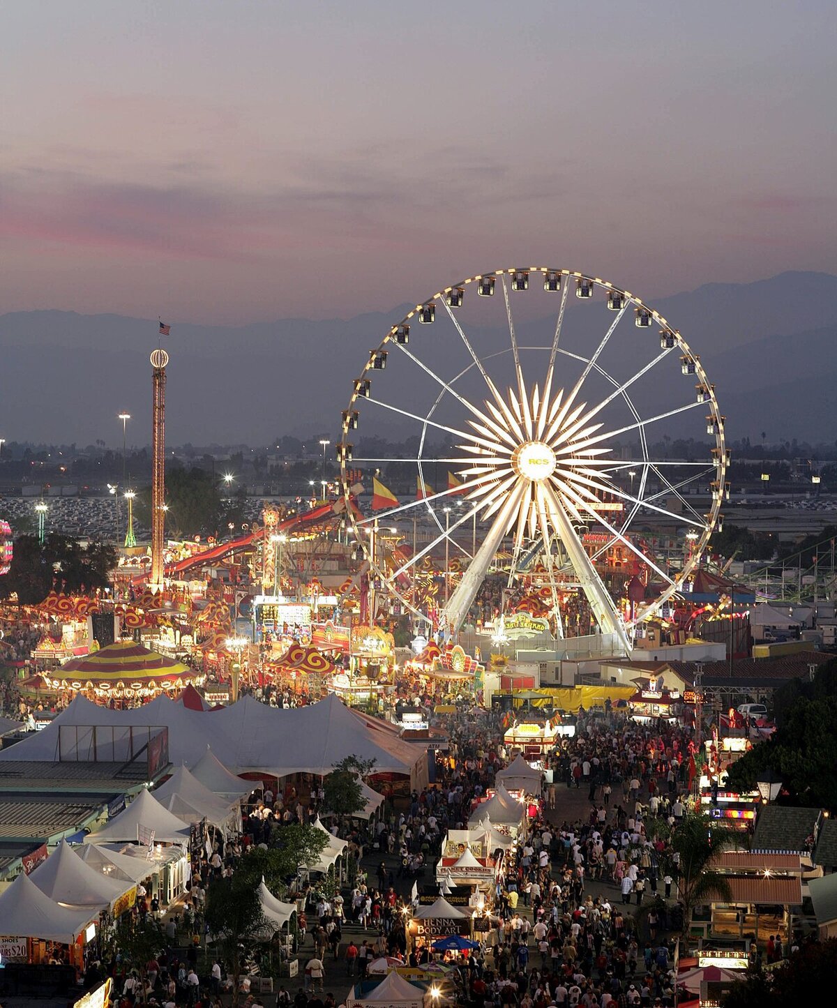 Lit Ferris wheel and crowded midway at dusk on the Fairplex fairgrounds in Pomona