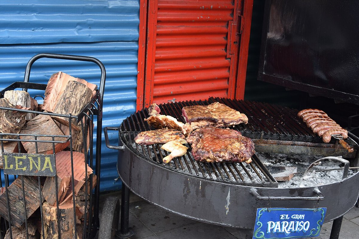 Grilled Argentine asado beef with charred crust on a cutting board, surrounded by side dishes