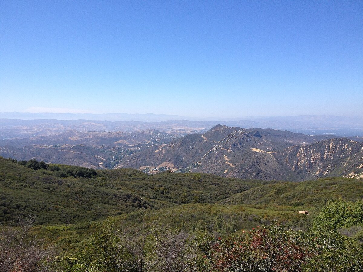 Wide view of green chaparral hills and ridgelines in Topanga Canyon under a clear blue sky