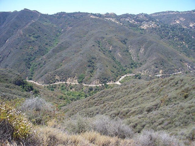 Hillsides of Topanga Canyon covered in chaparral, with a narrow road winding along the canyon floor