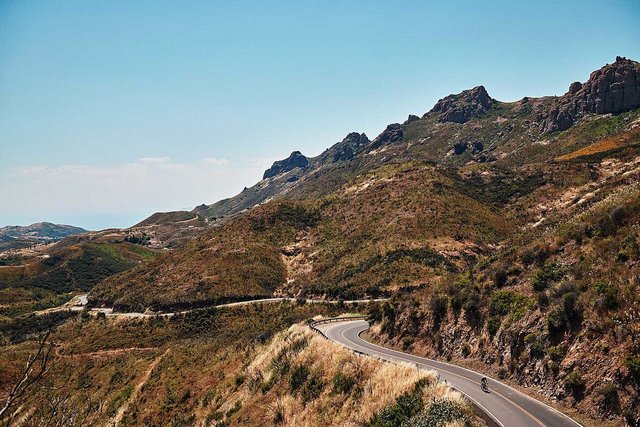 Winding road through chaparral-covered hills and rocky ridgelines in the Santa Monica Mountains under a clear sky