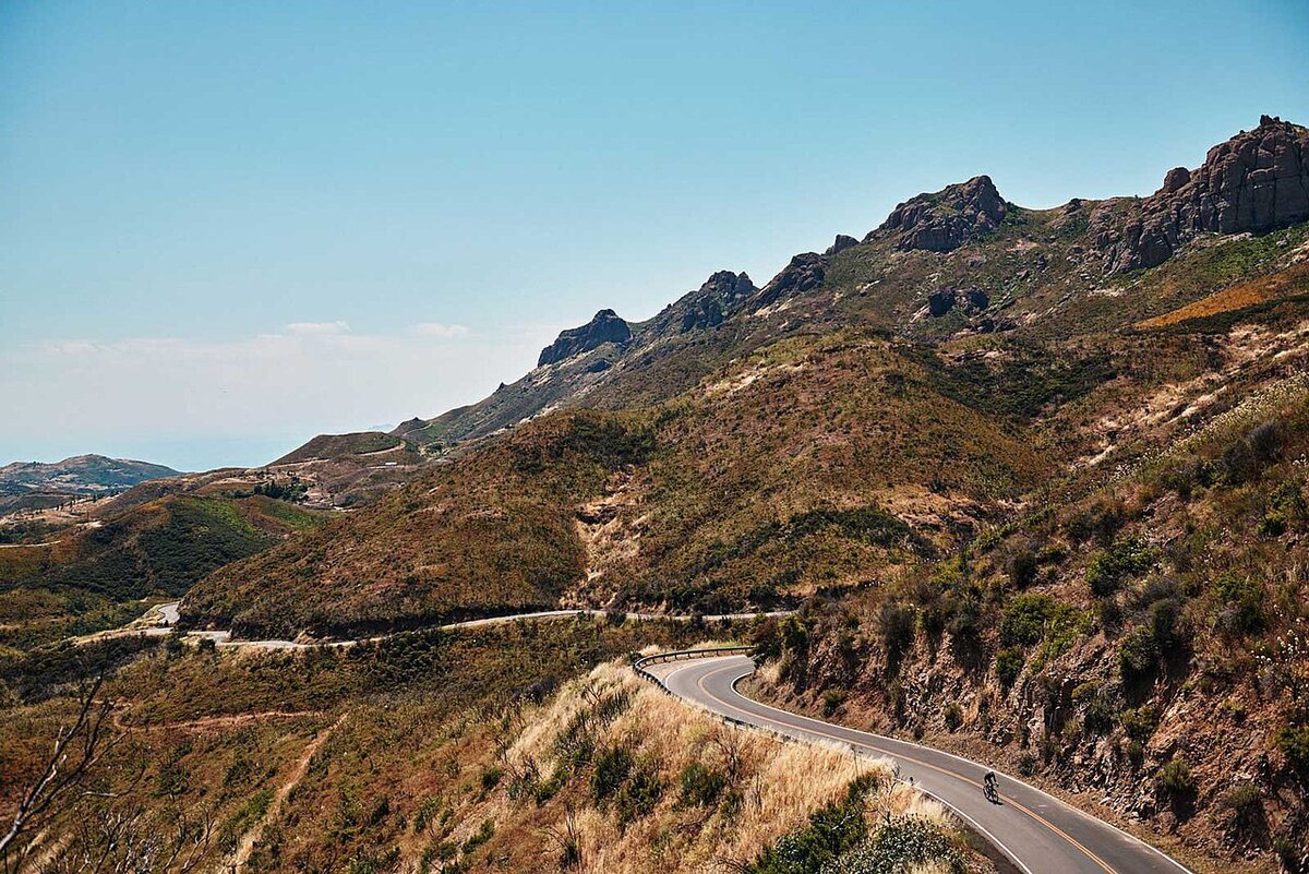Winding road through chaparral-covered hills and rocky ridgelines in the Santa Monica Mountains under a clear sky