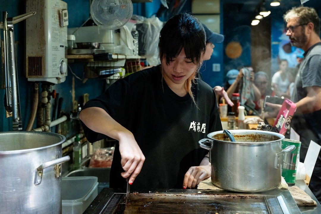 A young cook working at a griddle in a bustling kitchen, plating food with focus