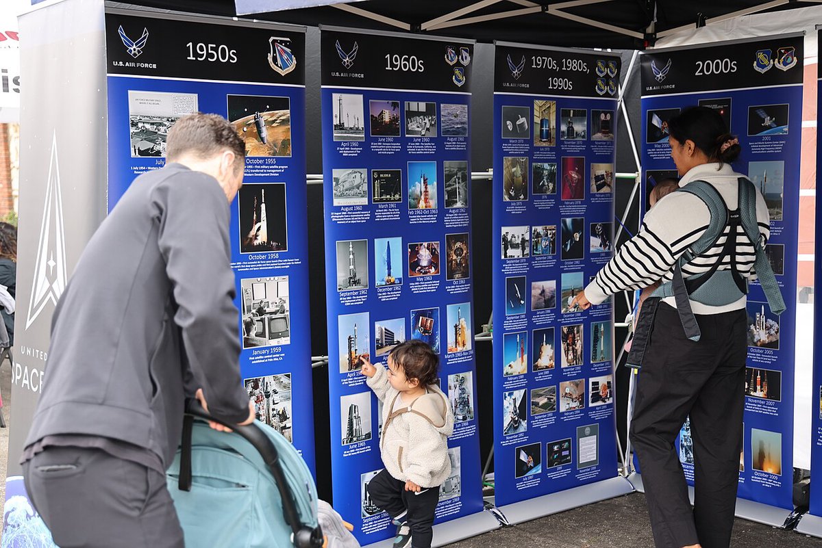 Residents gathered along a busy El Segundo Main Street event, reading display boards under a canopy