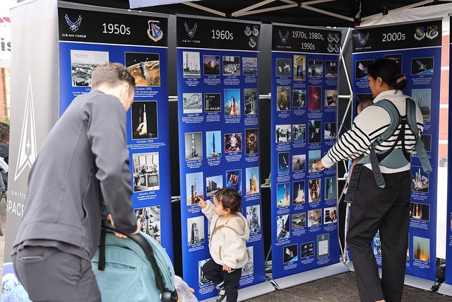 Residents gathered along a busy El Segundo Main Street event, reading display boards under a canopy