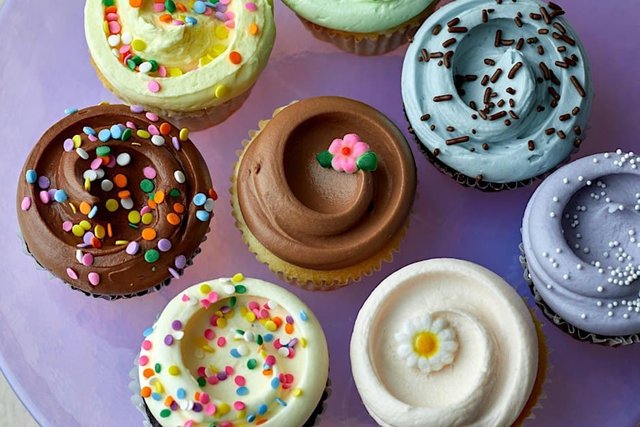 Overhead view of Magnolia Bakery cupcakes with swirled pastel and chocolate frosting, sprinkles and sugar flowers