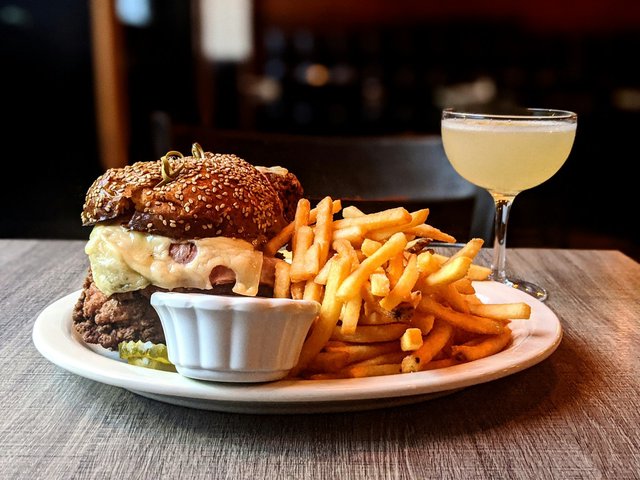 Six-ounce burger and a heap of fries on a white plate