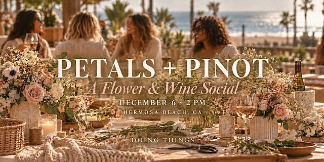 Long table set with flower arrangements, wine glasses and candles, with guests seated in front of a beach view