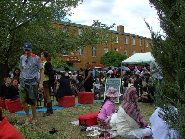 Colorful stalls and crowds at a Thai food festival, with vendors serving traditional dishes under bright banners