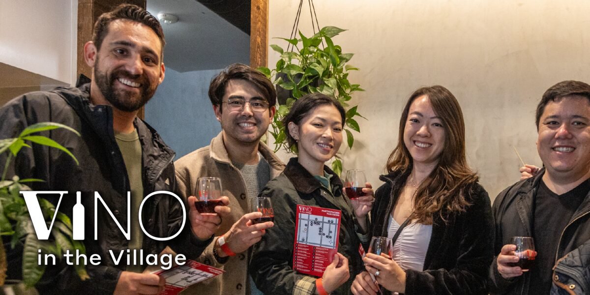 Five smiling friends holding glasses of red wine and a tasting map at Vino in the Village