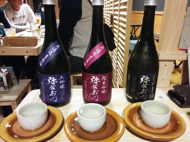 A server pouring sake for a group tasting session at a wooden bar