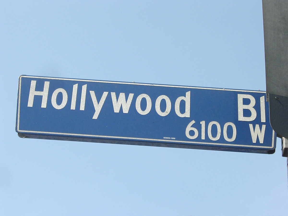 Blue Hollywood Boulevard street sign reading 6100 W against a clear sky