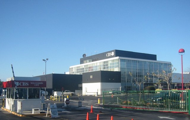 Entrance gate and studio building at CBS Television City on Beverly Boulevard under a clear blue sky