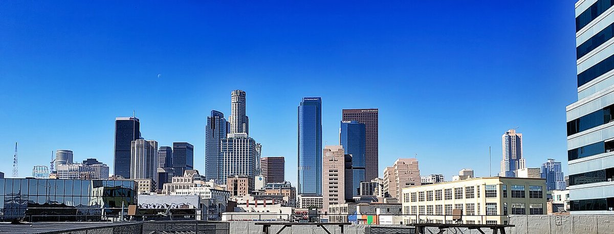Downtown Los Angeles skyline of glass towers under a clear blue sky, seen from a rooftop