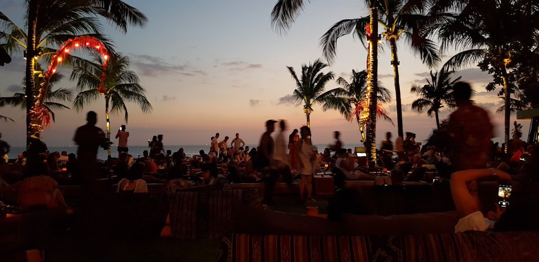 A group of people gathered at an outdoor gathering near a beach at sunset