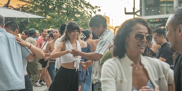 Dancers at an outdoor salsa night under string lights on a plaza