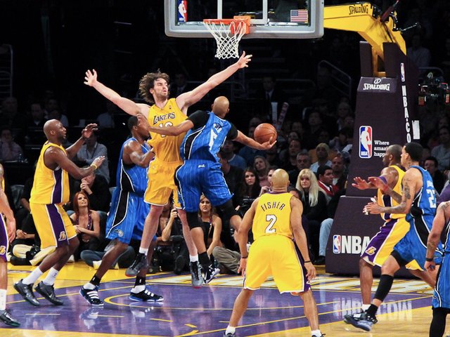 Pau Gasol in Lakers purple and gold defends against Vince Carter during an NBA game