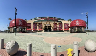 Angel Stadium's Home Plate entrance with two giant red Angels baseball caps and the Angel Stadium sign over the gate, on a sunny day