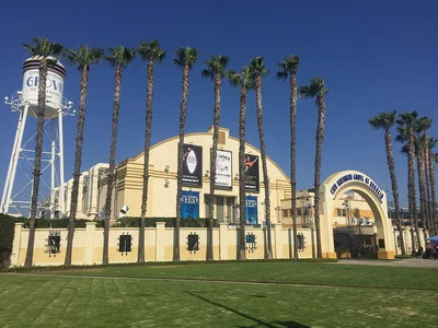 The cream-colored arched facade, palm trees and water tower of the DigAlert Grove of Anaheim, shown under its earlier City National Grove signage