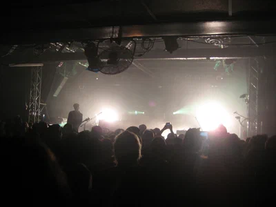 A packed crowd at the Echoplex facing a band lit from behind by white and green stage lights