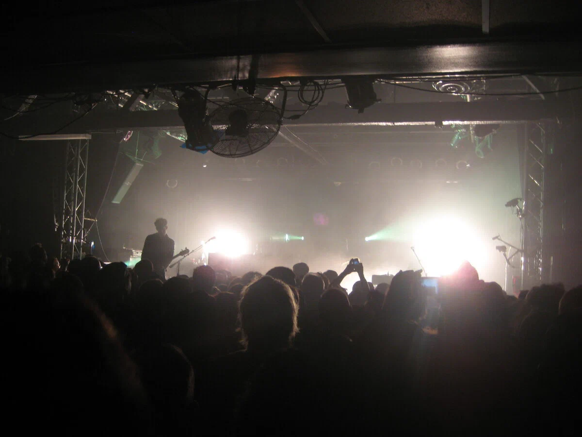 A packed crowd at the Echoplex facing a band lit from behind by white and green stage lights