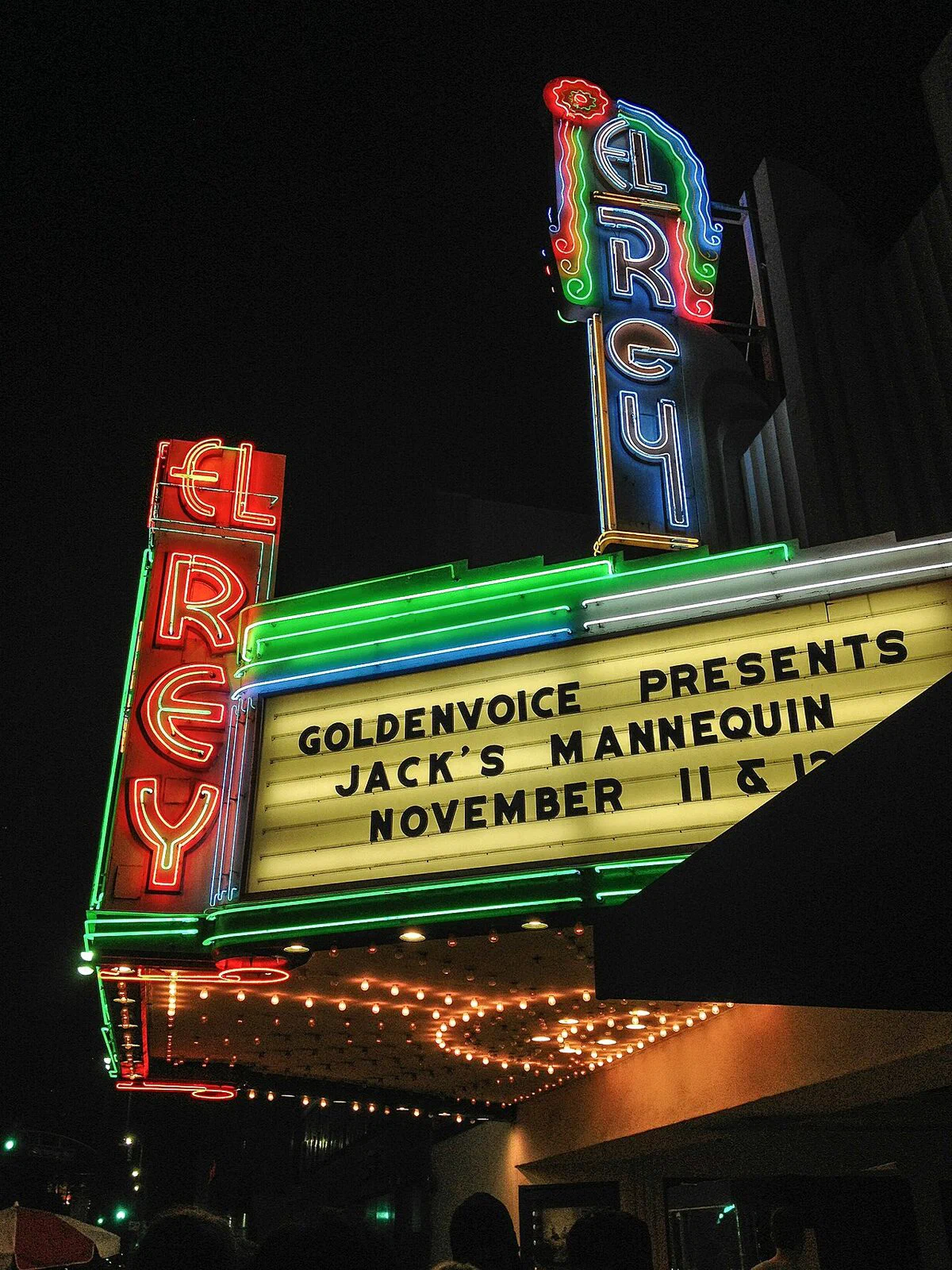 The El Rey Theatre's red, green and blue neon sign and lit marquee at night on Wilshire Boulevard