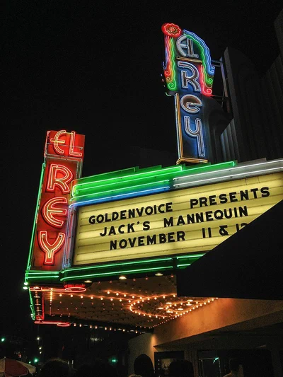 The El Rey Theatre's red, green and blue neon sign and lit marquee at night on Wilshire Boulevard