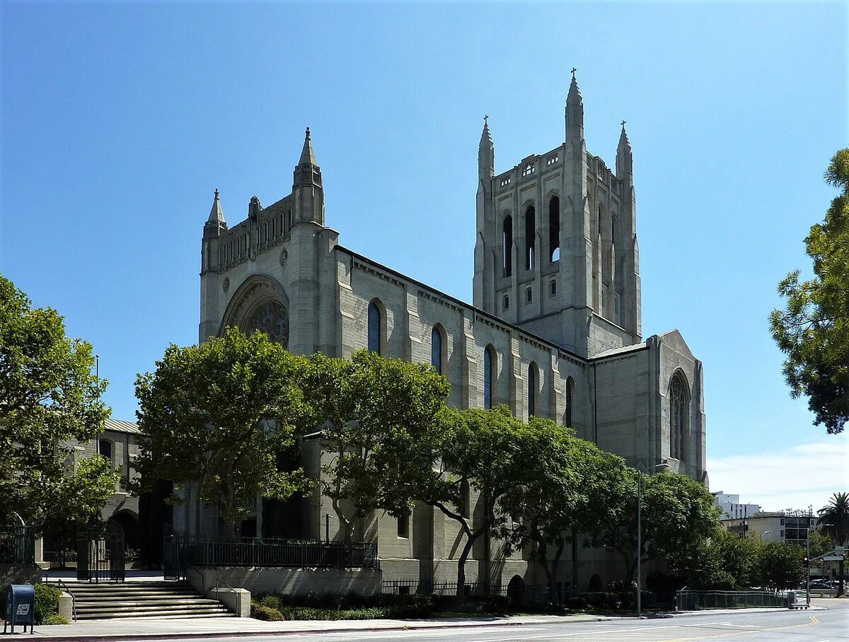 First Congregational Church of Los Angeles, a Gothic Revival stone church with a square bell tower, seen from across the street under a blue sky