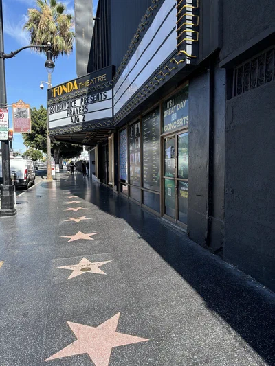 The Fonda Theatre marquee and black front on Hollywood Boulevard, with Walk of Fame stars on the sidewalk