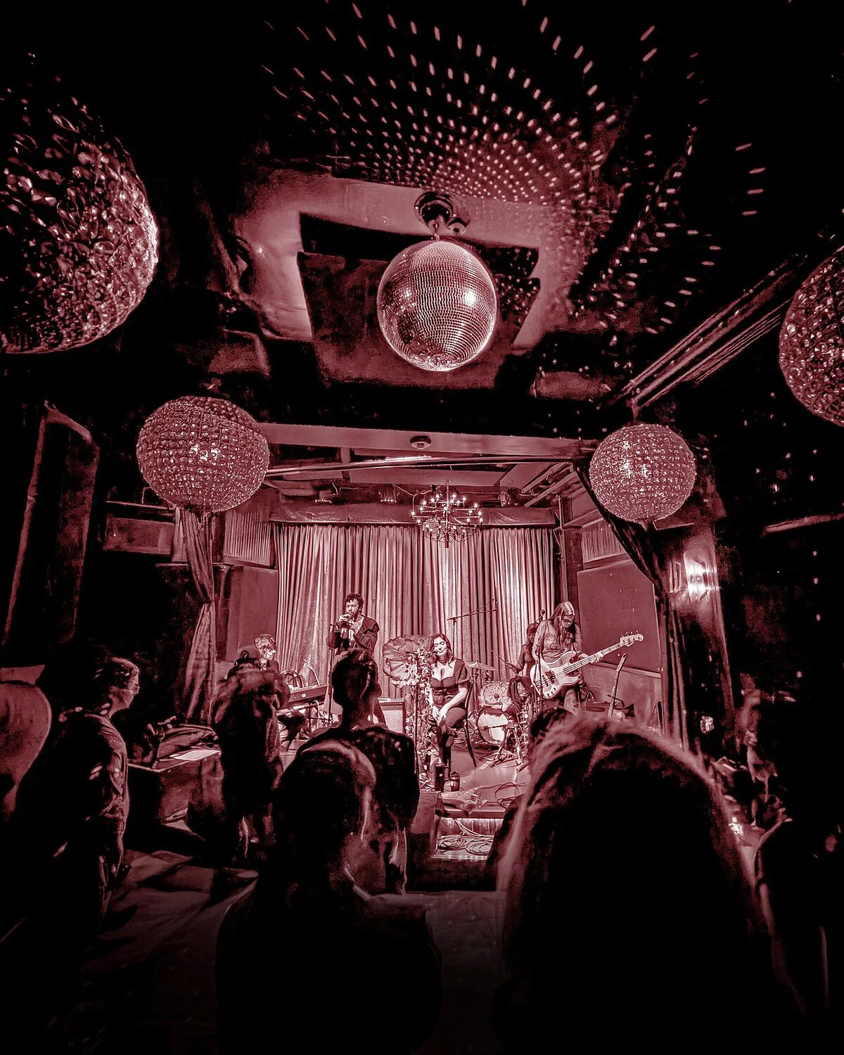 The bar room at Gold-Diggers during a show, with disco balls and chandeliers over the crowd and the curtained stage