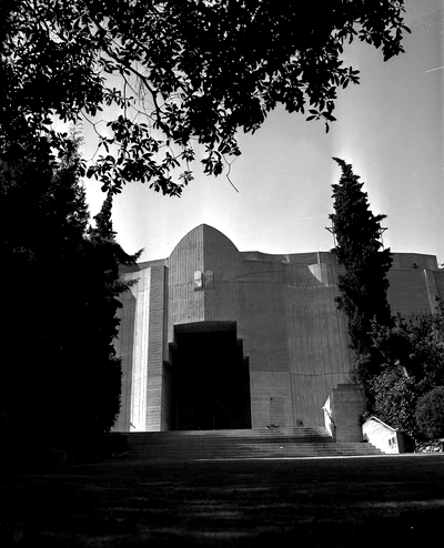 A 1956 black-and-white photo of the Ford's concrete entrance building and front steps, framed by trees and tall cypresses