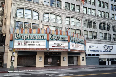 The Orpheum Theatre's three-part marquee under the ornate white facade of its building on Broadway in downtown Los Angeles