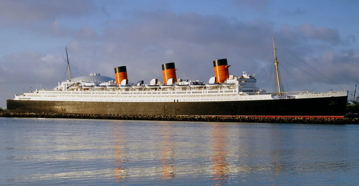 The Queen Mary ocean liner moored at Long Beach with her three funnels at dusk