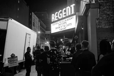 The Regent Theater's lit marquee on Main Street at night, with a line of people waiting outside