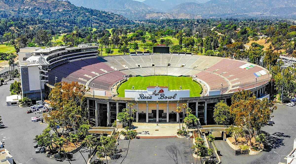 Aerial view of Rose Bowl Stadium's oval bowl and green field, with the Rose Bowl sign over the entrance and the San Gabriel foothills behind