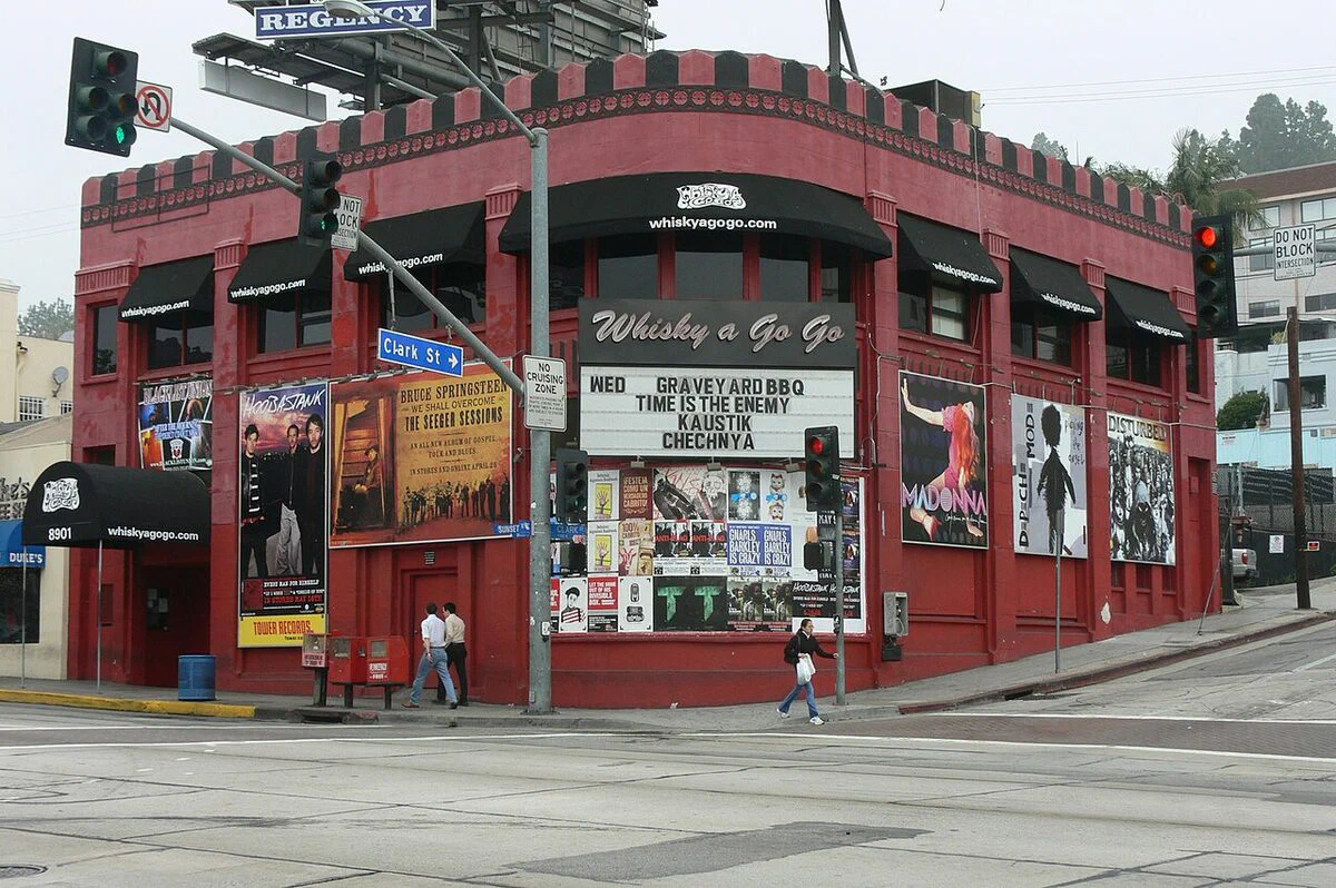 Whisky a Go Go's red corner building at Sunset and Clark with black awnings, a marquee and band posters on the walls