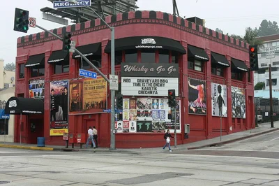 Whisky a Go Go's red corner building at Sunset and Clark with black awnings, a marquee and band posters on the walls